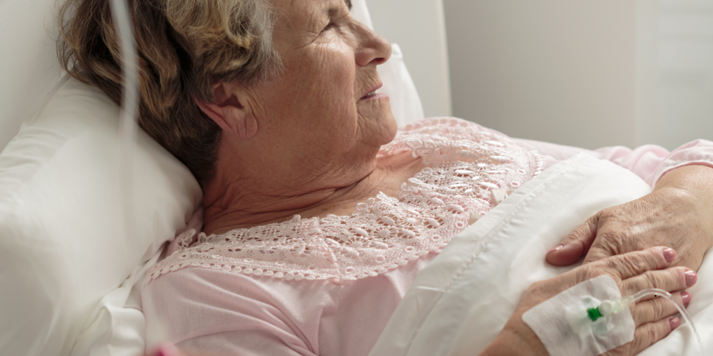 Elderly woman resting in a hospital bed with IV line, highlighting healthcare and long-term care needs in retirement