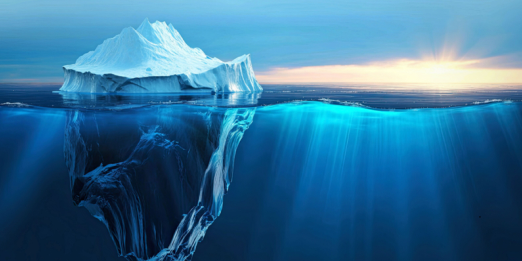 Iceberg floating in calm ocean water with a much larger portion hidden beneath the surface 