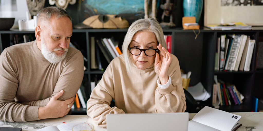 Mature couple reviewing retirement account statements together on a laptop at home