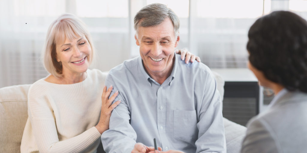 Smiling senior couple reviewing paperwork with a financial advisor during a retirement planning meeting